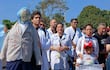 Grupo de médicos en batas blancas sostiene pancartas de protesta, un muñeco de 'Oscar Lovera' destaca en la escena.