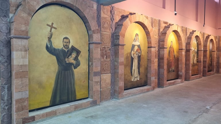 Murales de figuras religiosas en arcos, con iluminación que resalta la belleza del arte en el Museo Viedma.