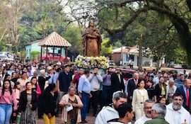 Multitud durante la procesión, con la Virgen María adornada con flores, en un ambiente de solemnidad y devoción.