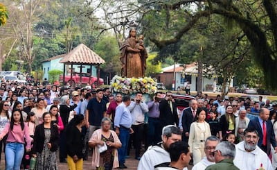 Multitud durante la procesión, con la Virgen María adornada con flores, en un ambiente de solemnidad y devoción.