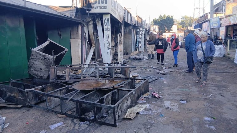 Horacio Fernández conversando con comerciantes en una calle comercial con estructuras dañadas y escombros visibles.
