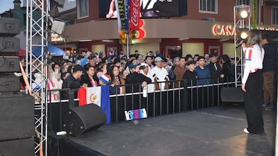 Una mujer con micrófono y un niño en el escenario, mientras el público celebra con camisetas de la selección paraguaya.
