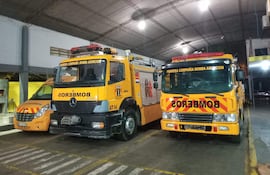 Dos camiones de bomberos de color amarillo y rojo estacionados en un garaje, pertenecientes a la Primera Compañía de Bomberos Asunción.