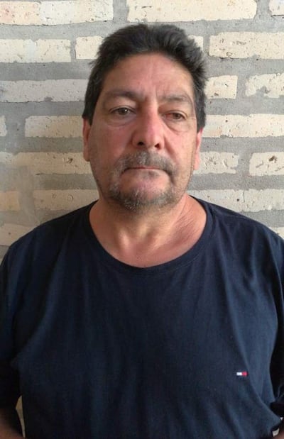 Hombre de mediana edad con cabello canoso y camiseta negra, mirándose a la cámara frente a una pared de ladrillos.