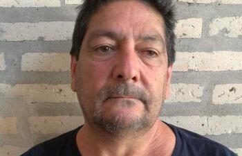 Hombre de mediana edad con cabello canoso y camiseta negra, mirándose a la cámara frente a una pared de ladrillos.