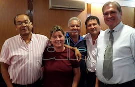 Emiliano Rolón sonríe con cuatro magistrados en un ambiente formal, vistiendo camisas de colores claros y oscuros con corbatas.
