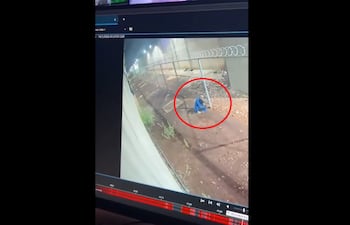 Uno de los reos fugados cortando el tejido intermedio entre el patio y el muro perimetral, durante el escape del penal de Minga Guazú, en la madrugada de este lunes.