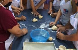 Un grupo de mujeres participa de un curso de panadería, con los elementos de protección dados por la Sinafocal.