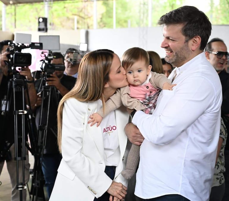 Soledad Núñez sonriente con chaqueta blanca, junto a Bruno Defelippe en camisa blanca, en un ambiente iluminado y de cobertura mediática.