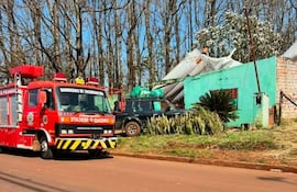 Camión de bomberos de Encarnación estacionado, con inmueble verde dañado al fondo y árboles desnudos en el ambiente.