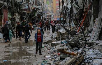 (FILES) Palestinians walk amid debris of buildings hit in Israeli strikes, near Al-Zawiya market in Gaza City on November 27, 2023, on the fourth day of a truce in fighting between Israel and Hamas. Bombed-out neighbourhoods, mass graves dug in the sand, spreading hunger and disease -- as the bloodiest ever Gaza war nears 100 days, besieged Palestinians have endured ever new horrors. (Photo by Omar El-Qattaa / AFP)