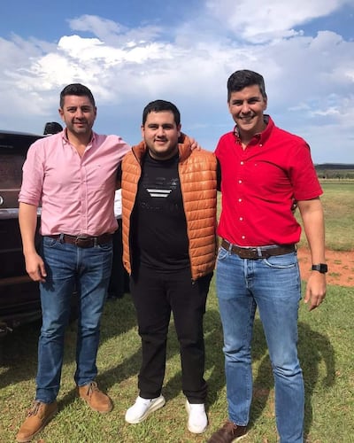 José Emilio con naranja, Pedro Alliana con camisa rosa y Santiago Peña con camisa roja, sonríen en un entorno tranquilo con césped verde.
