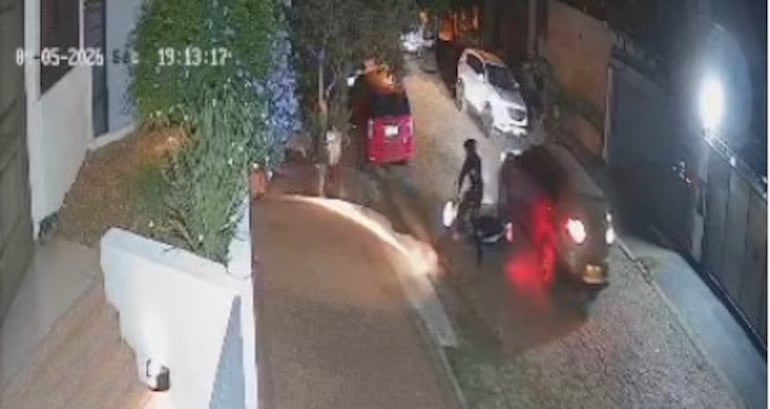 La camioneta de los maleantes retrocede y golpea la moto del patrullero que cae sobre el pavimento.