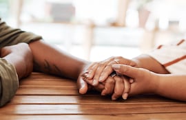 Una mujer toma de la mano a un hombre, en señal de apoyo.