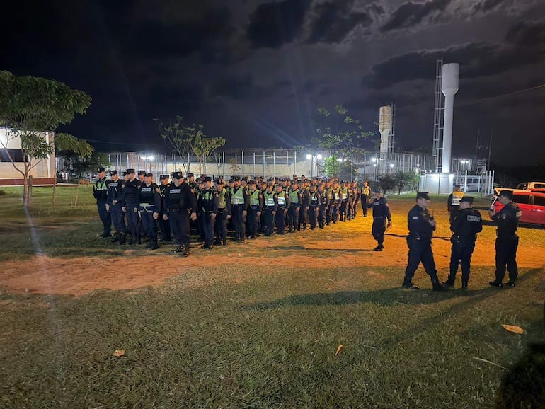Grupo de agentes policiales en formación, vistiendo uniformes negros y verdes, en una zona iluminada durante la requisa en la penitenciaría.