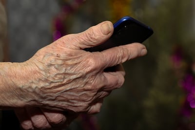 Una mujer anciana manipula un teléfono celular.