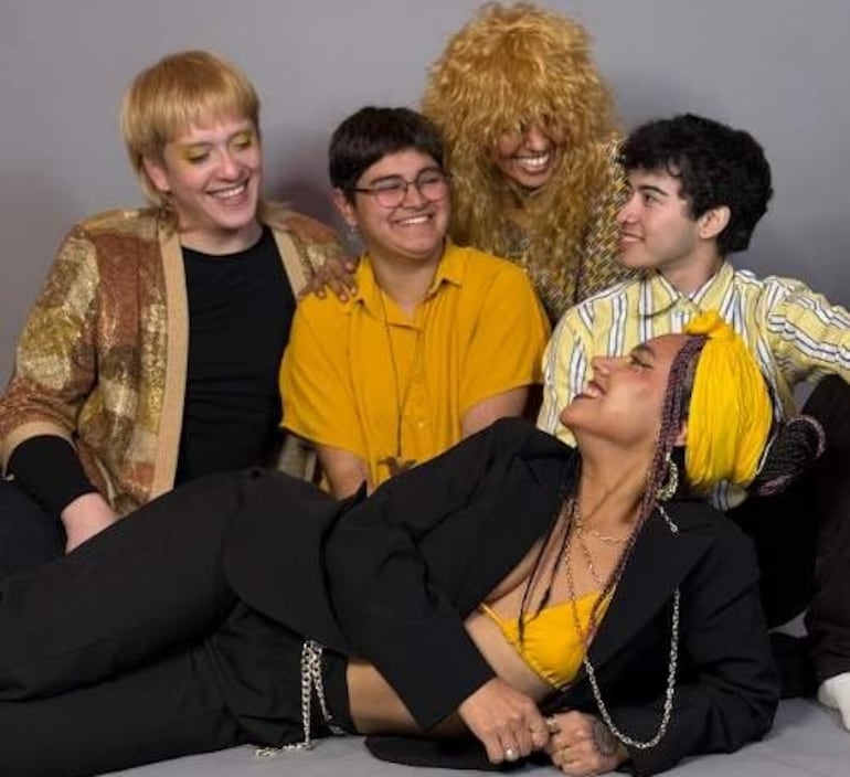 Cinco personas sonrientes en fondo gris: mujer con pañuelo amarillo y chico alegre, con atuendos amarillos y oscuros.