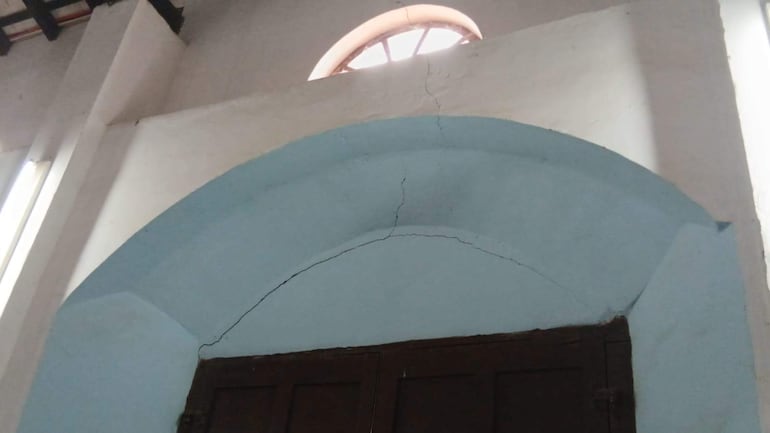 Interior de la Catedral de San Pedro Apóstol, con un arco azul y grietas en la pared, iluminado por luz natural.