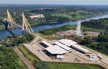 Puente de la Integración en tonos amarillos y grises, cruzando un río, rodeado de vegetación densa y un complejo arquitectónico cercano.