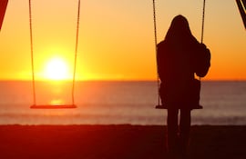 Mujer se hamaca sola mientras mira el atardecer.
