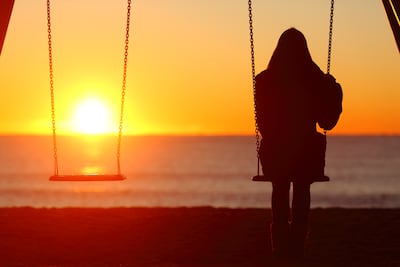 Mujer se hamaca sola mientras mira el atardecer.