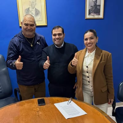 Chilavert en chaqueta negra, Achucarro Gill en vestimenta formal y Maldonado con chaqueta marrón, todos sonriendo en entorno azul.