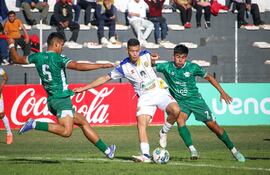 El delantero del Deportivo Capiatá, Alexis Acuña pisa el esférico rodeado por Emilio Blanco (5) y Juan Sebastián Cáceres. (Foto: @CopaParaguayAPF)