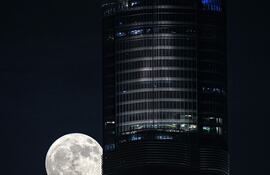 La Luna llena, también llamada Super Luna Azul, se eleva detrás del edificio más alto del mundo, Burj Khalifa, en el emirato del Golfo de Dubai, Emiratos Árabes Unidos.