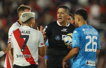 El árbitro Yael Falcón discute con el delantero número 07 de River Plate, Maximiliano Salas, y el defensor paraguayo número 26 de Tucumán, Clever Ferreira, durante el partido del Torneo Apertura 2026 de la Liga Argentina de Fútbol Profesional entre River Plate y Atlético Tucumán, en el estadio Mas Monumental de Buenos Aires, el 3 de mayo de 2026. (Foto de ALEJANDRO PAGNI / AFP)
