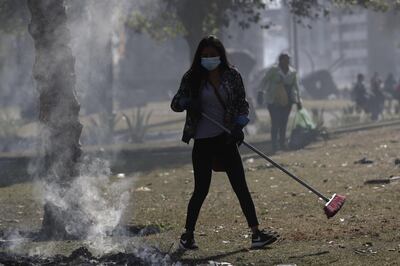 Un grupo de personas usa mascarillas sanitarias en las labores de limpieza de los escombros dejados por los disturbios en Quito.