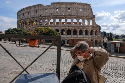 Un turista se coloca un barbijo al pasar frente al Coliseo, en Roma.
