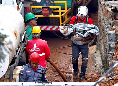 Un rescatista lleva un cadáver en una zona colapsada a causa de las lluvias en Belo Horizonte, Brasil.