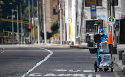 A cleaning worker wears a face mask as a preventive measure against the spread of the new coronavirus, COVID-19, in a street of Bogota on March 21, 2020. - Colombian President Ivan Duque announced mandatory preventive isolation from March 24 to April 13 as a measure against the spread of the novel coronavirus. (Photo by Juan BARRETO / AFP)