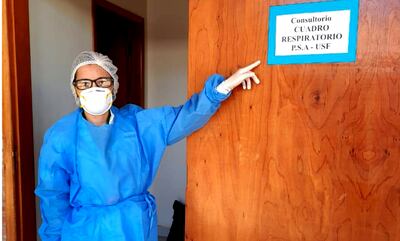 Una profesional del puesto de salud muestra el cartel del área para pacientes con cuadro respiratorio sospechoso.