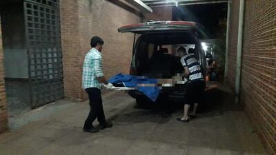 Funcionarios de una funeraria retiran el cuerpo de la mujer de la morgue del Hospital Regional de Concepción.