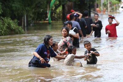 Habitantes de Ciledug, Tanggerang, En Indonesia, caminan en un área inundada.