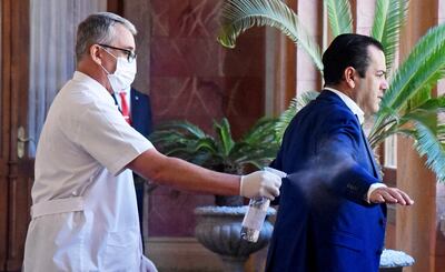 El ministro de Agricultura, Rodolfo Friedmann (der.),  es sometido al estricto protocolo sanitario en el Palacio de López.
