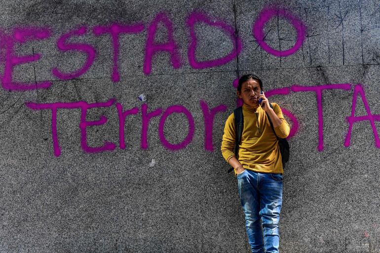 Un hombre habla por teléfono junto a una pared pintada con la leyenda "Estado terrorista" en Santiago de Chile.