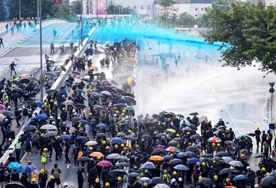 Manifestantes hongkoneses, con paraguas, símbolo de las protestas prodemodráticas, son repelidos por hidrantes de la policía de esa región autónoma china, cuyas autoridades son funcionales a la dictadura comunista que rige en el resto del país.