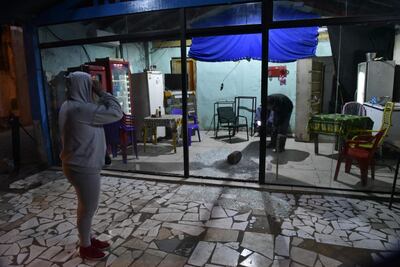 La dueña del sitio mira el interior de su local asaltado.