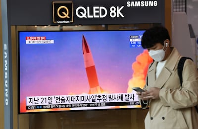 Un hombre pasa junto a una pantalla que muestra imágenes de una prueba de misil norcoreana.
