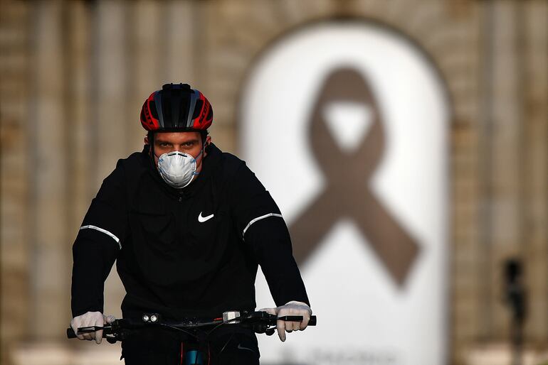 Un ciclista con mascarilla frente a la Puerta de Alcalá en Madrid, España.