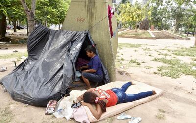 Una mujer indígena acostada en un colchón en el piso, frente a una de las carpas que forma parte del campamento improvisado.