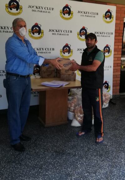 El gerente del club, David Argüello (i), hace entrega uno de los kits a uno de los profesionales relacionados al turf.