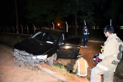 Bomberos y un agente de policía inspeccionan el vehículo abandonado en el ramal Areguá-Capiatá.