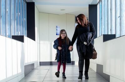Iria, una niña de 10 años con una mutación genética ultrarrara y que se ha convertido en el primer paciente pediátrico triple trasplantado de corazón, hígado y riñón de España, camina con su madre Judith por un pasillo del Hospital Vall d'Hebron de Barcelona, poco antes de la rueda de prensa que han ofrecido junto al equipo médico que la ha tratado.