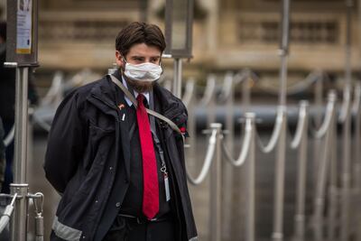 Un guardia de seguridad con tapabocas cerca de la pirámide del Museo Louvre de París, Francia.