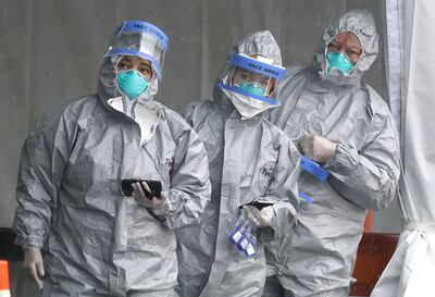 Personas con trajes de protección se preparan para realizar pruebas de COVID-19 en un centro de testeo en Nueva Rochelle, Nueva York.