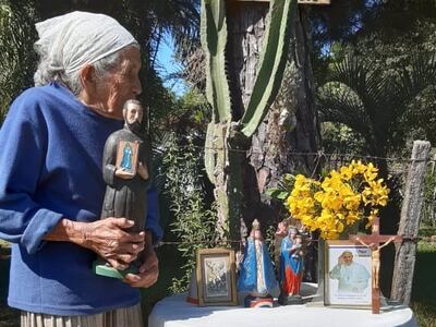 Una devota mujer aguarda junto a sus imágenes religiosas.