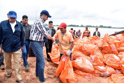 El presidente Mario Abdo (c) saluda a un funcionario designado a las tareas de limpieza en Itapytãpunta, en Asunción. A su lado, el titular de la SEN, Joaquín Roa.